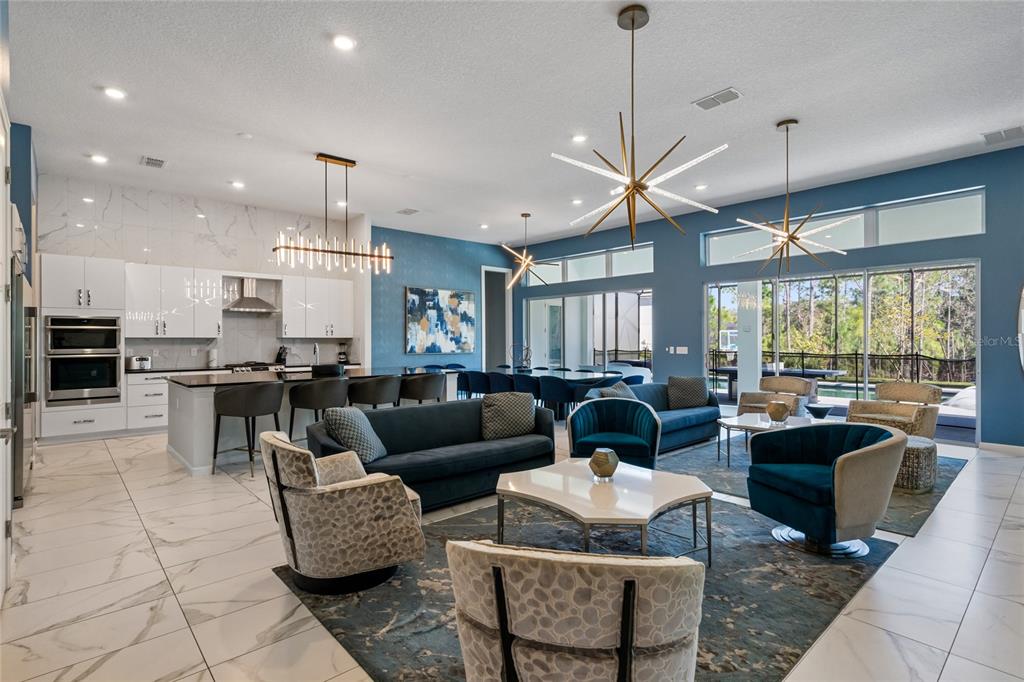 An open-concept living and kitchen area features blue walls, marble flooring, and modern starburst lighting — 1758 OAK BLOSSOM DRIVE, DAVENPORT, FL