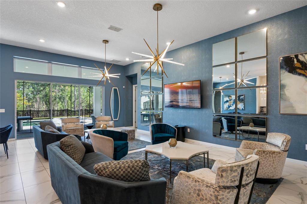 A living room features blue walls, a large mirror grid, modern chandeliers, and patterned armchairs — 1758 OAK BLOSSOM DRIVE, DAVENPORT, FL