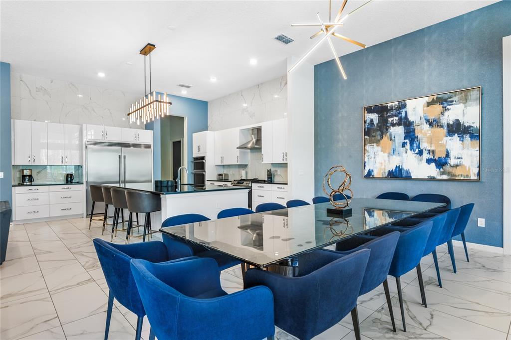 A modern open-concept kitchen and dining area featuring blue accent walls and white cabinetry — 1758 OAK BLOSSOM DRIVE, DAVENPORT, FL