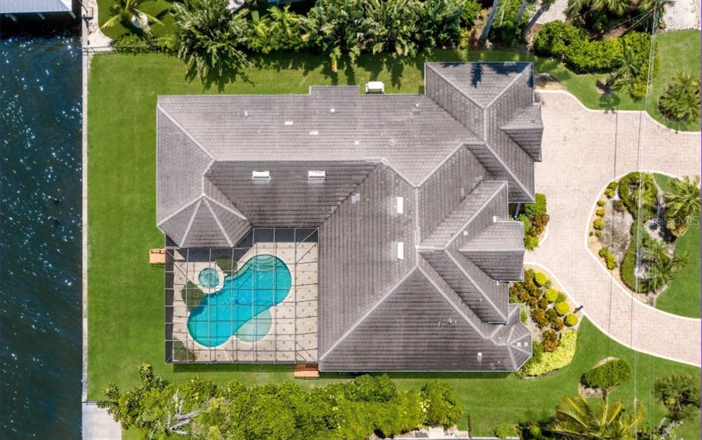 An aerial view shows a house with a tiled roof, a screened pool, and landscaping — 5904 RIVERVIEW BOULEVARD, BRADENTON, FL