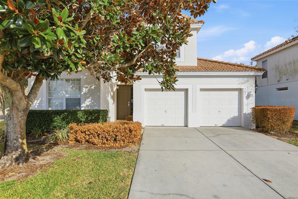 A two-story house with a white stucco exterior, two garage doors, and a front lawn — 2621 ARCHFELD BOULEVARD, KISSIMMEE, FL