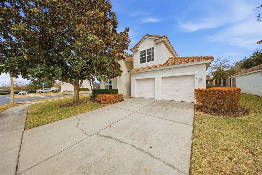 A two-story house with a two-car garage, a concrete driveway, and a large magnolia tree — 2621 ARCHFELD BOULEVARD, KISSIMMEE, FL