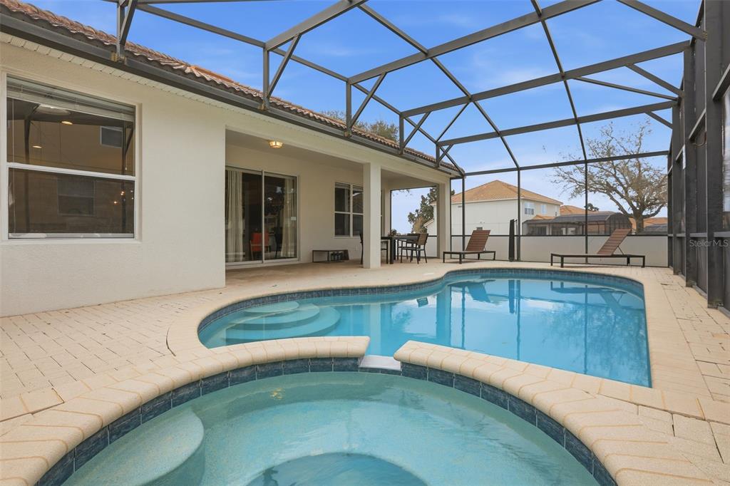 A screened-in patio features a swimming pool, a spa, and lounge chairs — 2621 ARCHFELD BOULEVARD, KISSIMMEE, FL