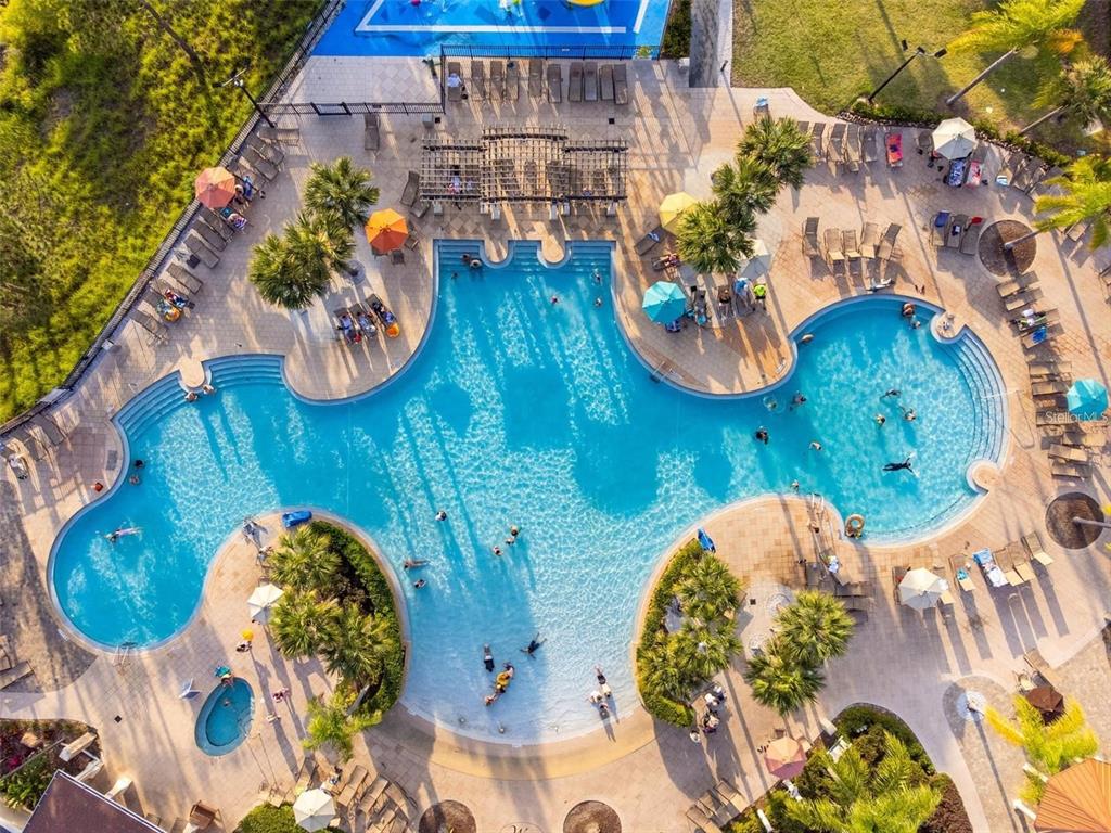 An aerial view shows a large swimming pool with lounge chairs, umbrellas, and palm trees — 2621 ARCHFELD BOULEVARD, KISSIMMEE, FL
