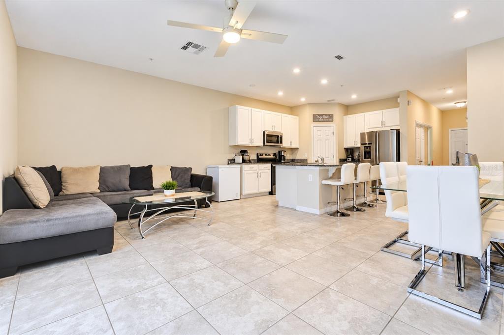 A living room features tile flooring, a sectional sofa, a glass coffee table, and sliding doors — 2163 CRYSTAL BELL STREET, ORLANDO, FL