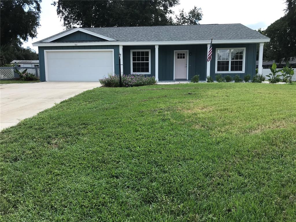 A grassy, sloped lot sits in front of a white fence and distant houses — 707 HARDY WAY, AUBURNDALE, FL