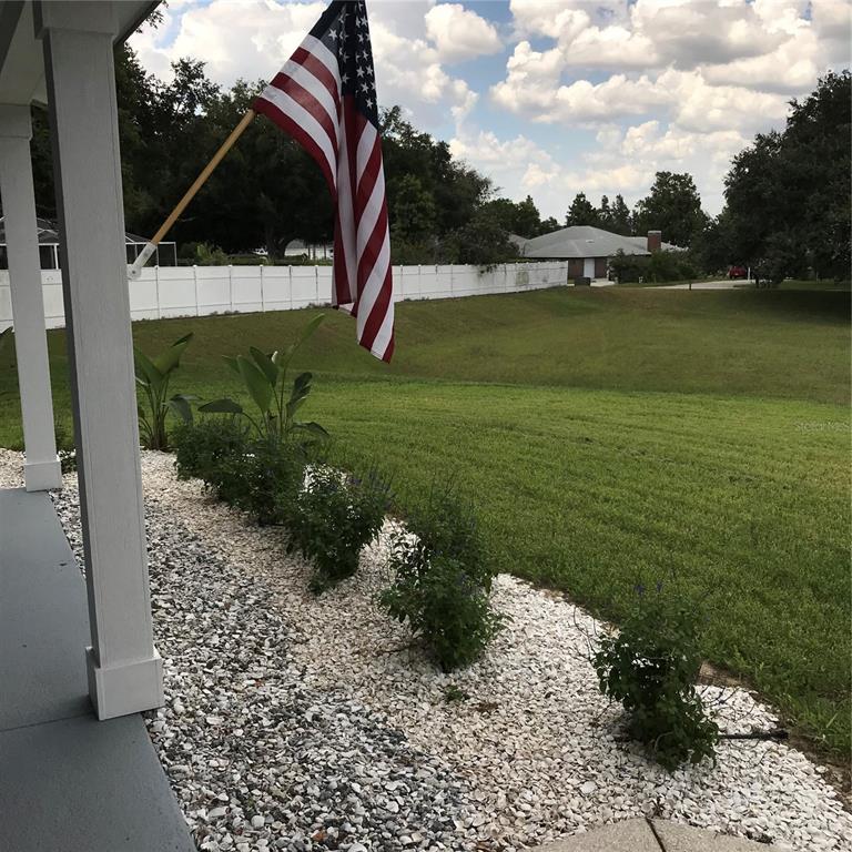 A view from a porch looking out over a white gravel garden bed and lawn — 707 HARDY WAY, AUBURNDALE, FL