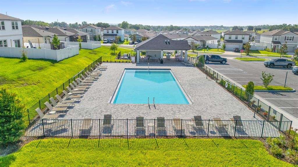 An outdoor community swimming pool with lounge chairs and a covered pavilion — 38465 HONEYSUCKLE DRIVE, DADE CITY, FL