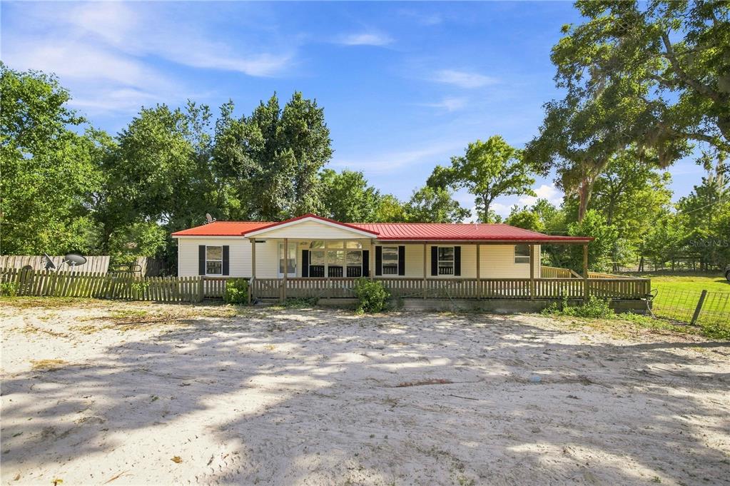 A single-story manufactured home with a red metal roof and a full-length wooden front porch — 2251 SE 136TH AVENUE, MORRISTON, FL