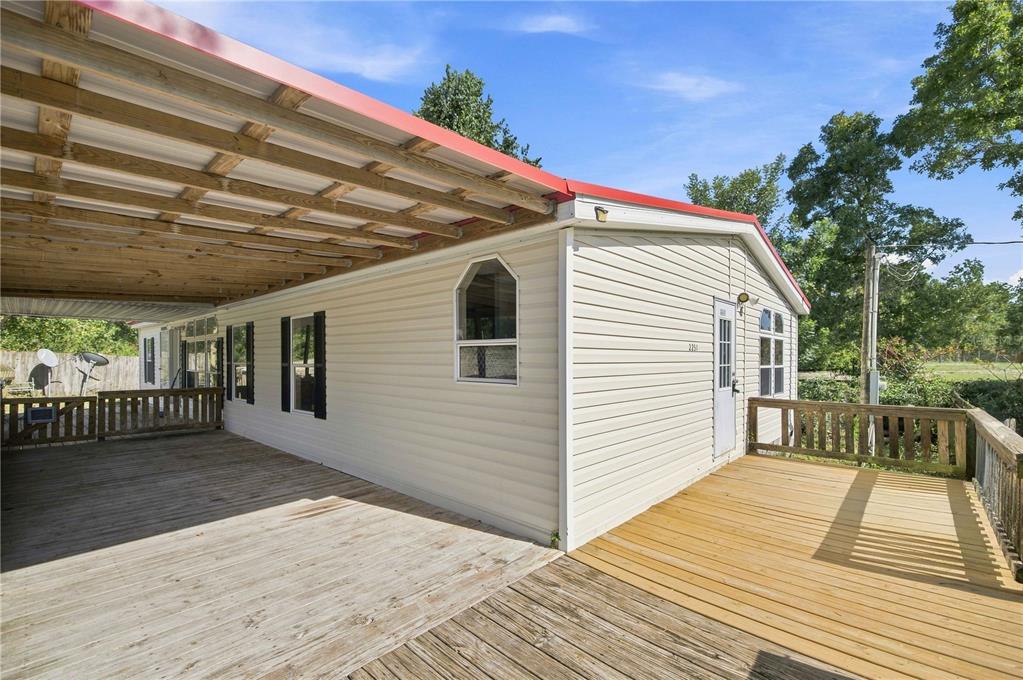 A mobile home exterior features a large wooden deck and a covered porch area — 2251 SE 136TH AVENUE, MORRISTON, FL