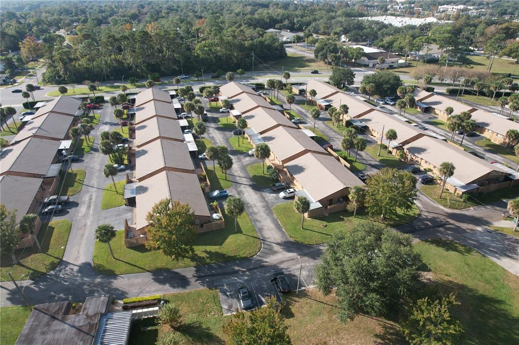 An aerial view shows multiple rows of single-story apartment buildings with parking spaces and palm trees — 474 C STREET, CASSELBERRY, FL