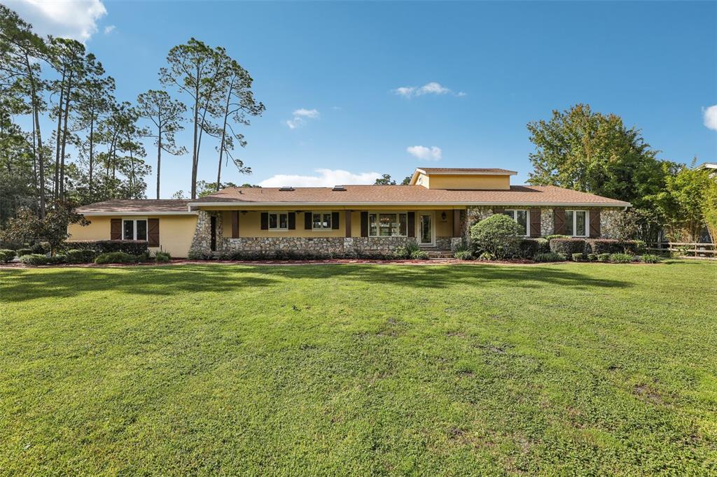 A single-story ranch house with a stone facade and a large front lawn — 11450 FANGORN ROAD, ORLANDO, FL