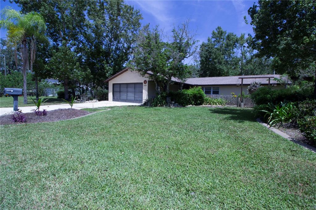 A single-story house with a garage and a large front lawn under a blue sky — 8609 HORIZON LANE, HUDSON, FL