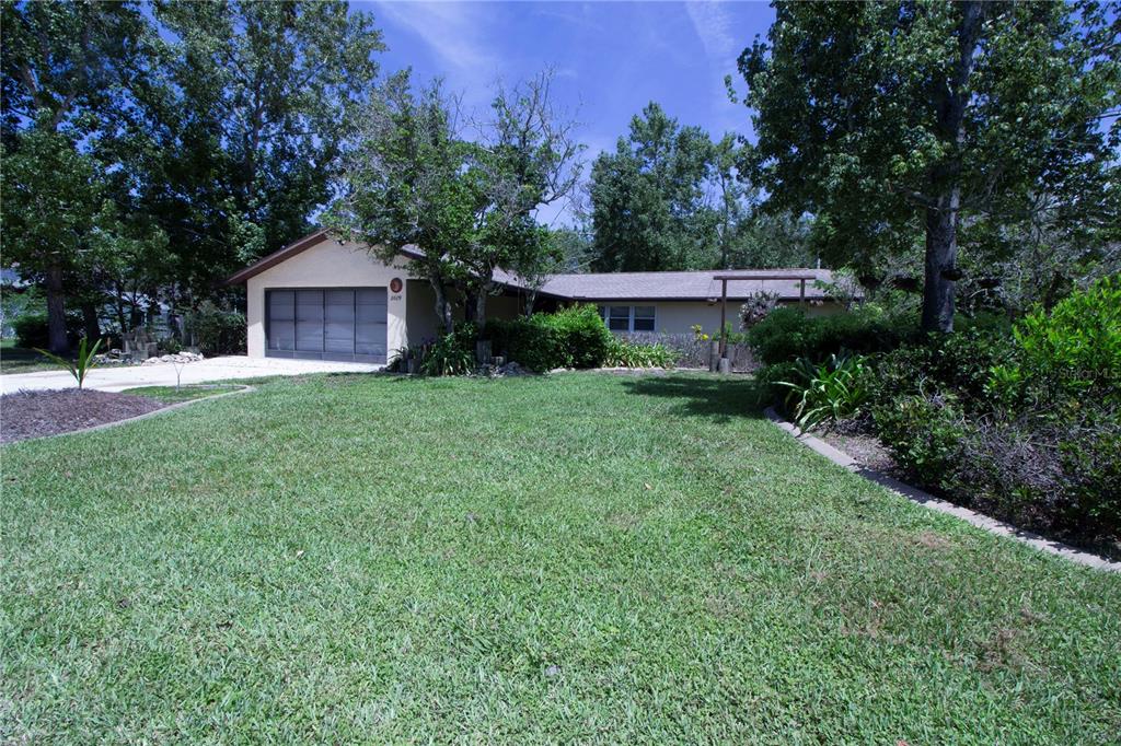 A single-story house with a two-car garage sits behind a large, grassy front yard — 8609 HORIZON LANE, HUDSON, FL