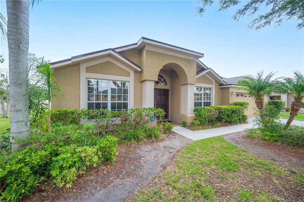 A single-story tan stucco house with a covered entryway and a landscaped front yard — 101 KIANA DRIVE, BRANDON, FL