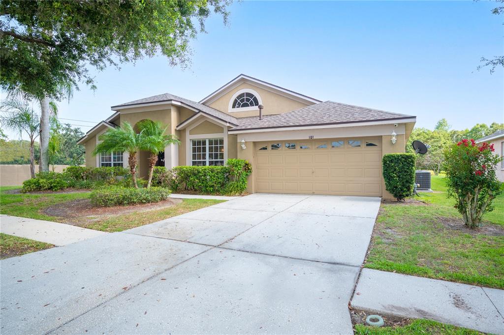 A single-story house with a tan stucco exterior, a two-car garage, and a concrete driveway — 101 KIANA DRIVE, BRANDON, FL