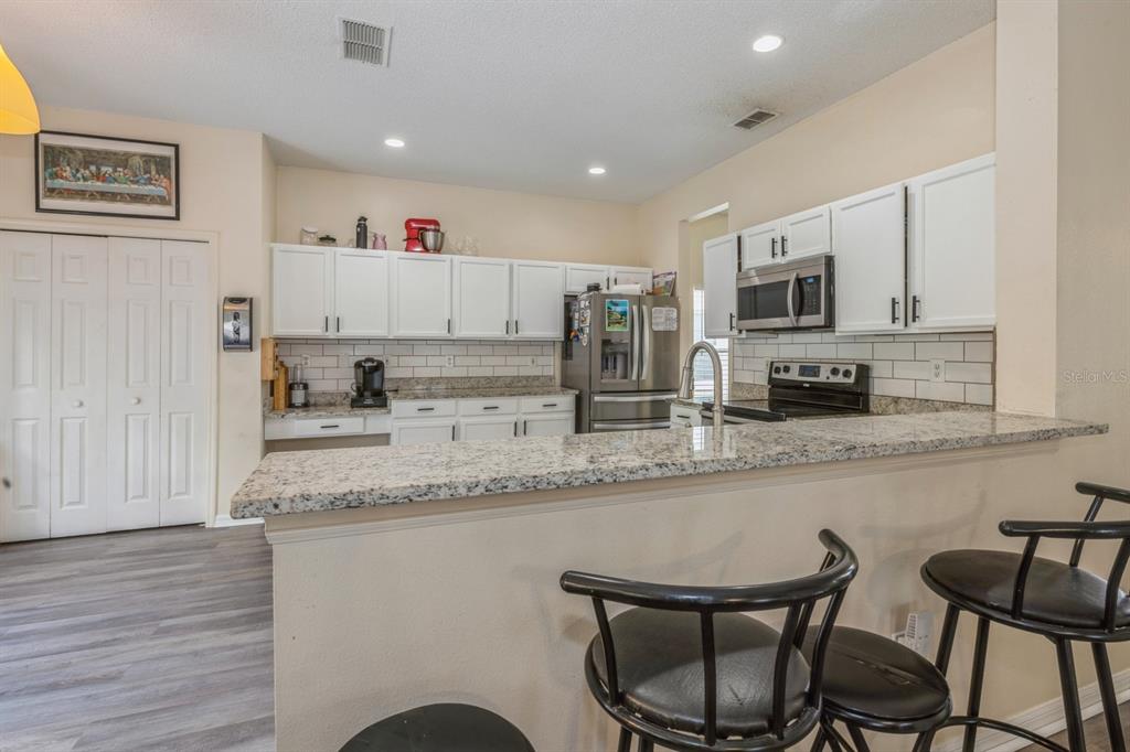 A kitchen features white cabinets, granite countertops, stainless steel appliances, and a breakfast bar — 502 FREEMAN STREET, LONGWOOD, FL