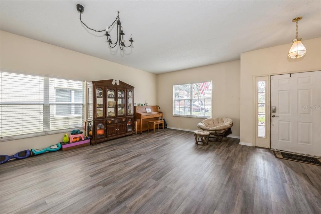 A living room with wood-look flooring, a piano, a china cabinet, and a front door — 502 FREEMAN STREET, LONGWOOD, FL