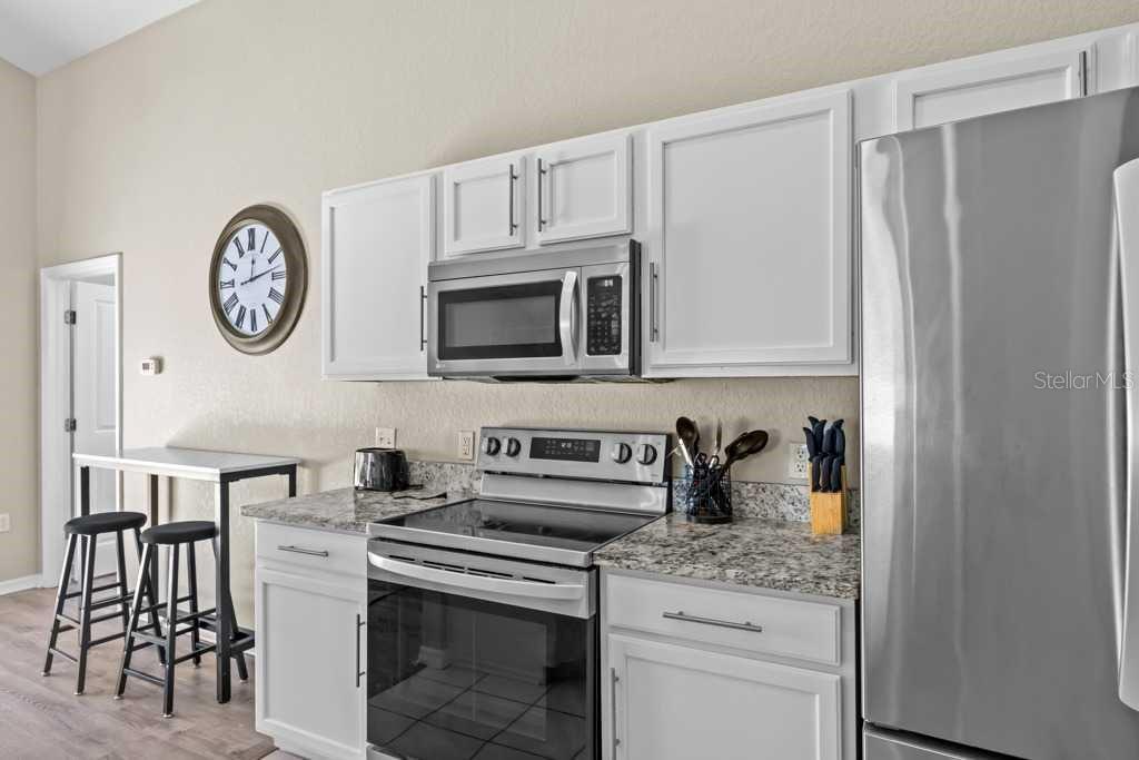 A kitchen features white cabinets, stainless steel appliances, and granite countertops — 641 RESERVE DRIVE, DAVENPORT, FL