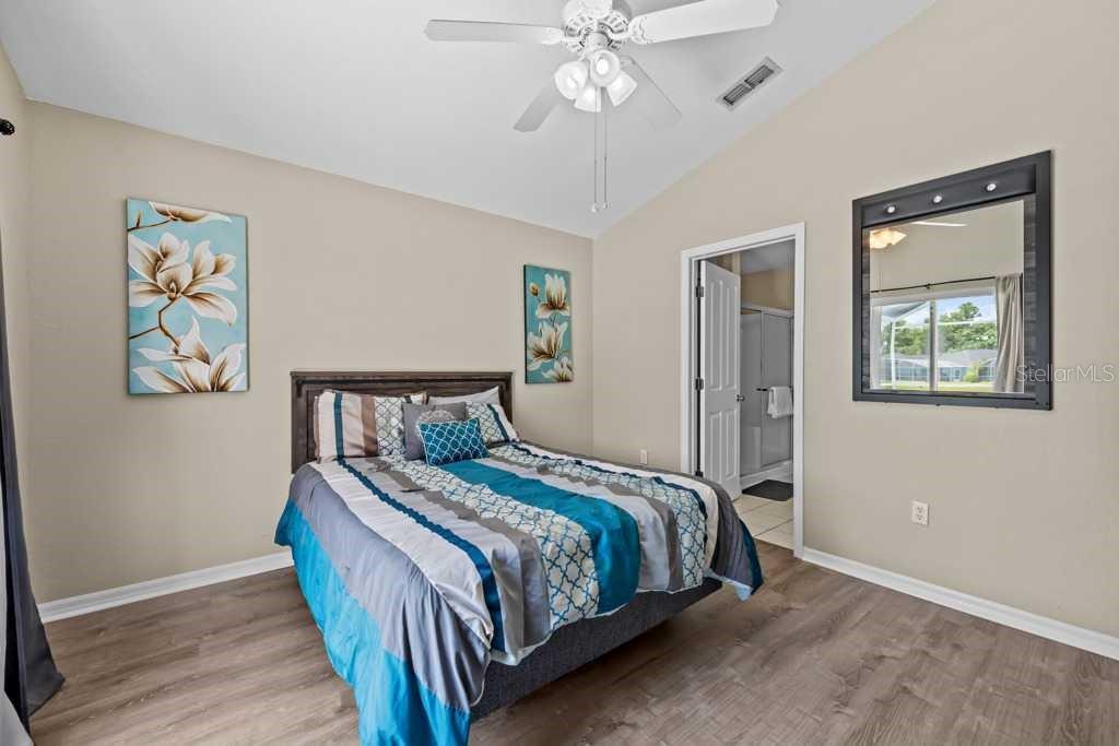 A bedroom features a bed with blue and gray bedding, wall art, and a mirror — 641 RESERVE DRIVE, DAVENPORT, FL