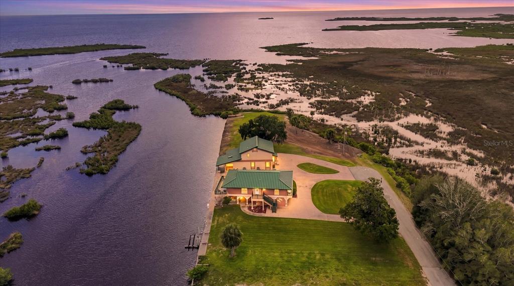 An aerial view shows a house with a green roof situated along a coastal waterway — 3194 INDIAN GULF LANE, HERNANDO BEACH, FL