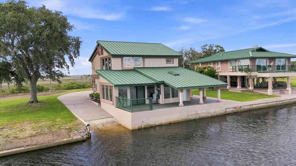 A two-story house with a green metal roof sits directly on a canal waterfront — 3194 INDIAN GULF LANE, HERNANDO BEACH, FL