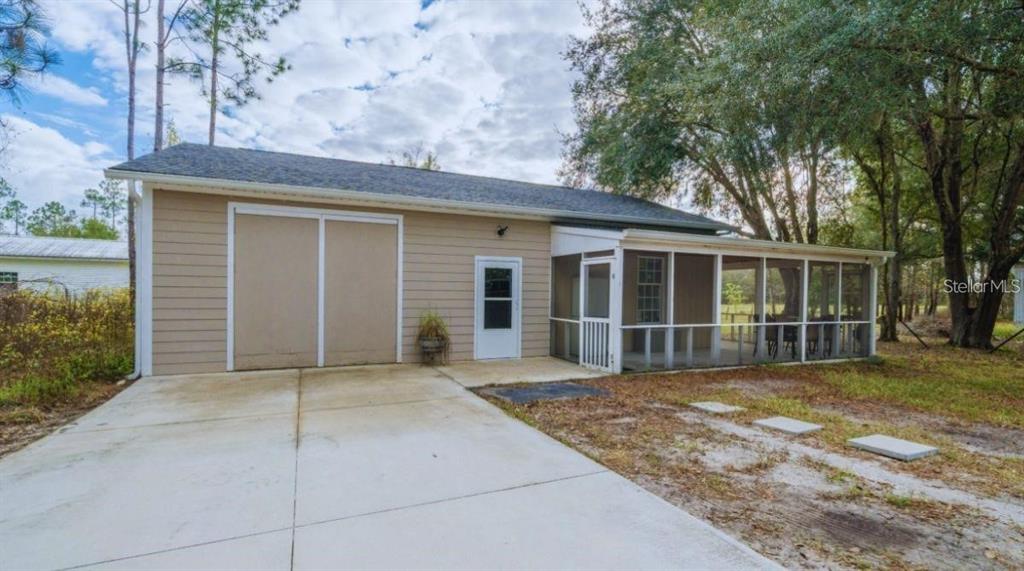 A tan-sided detached garage with a concrete driveway and an attached screened-in porch — 19751 COUNTY ROAD 33, GROVELAND, FL