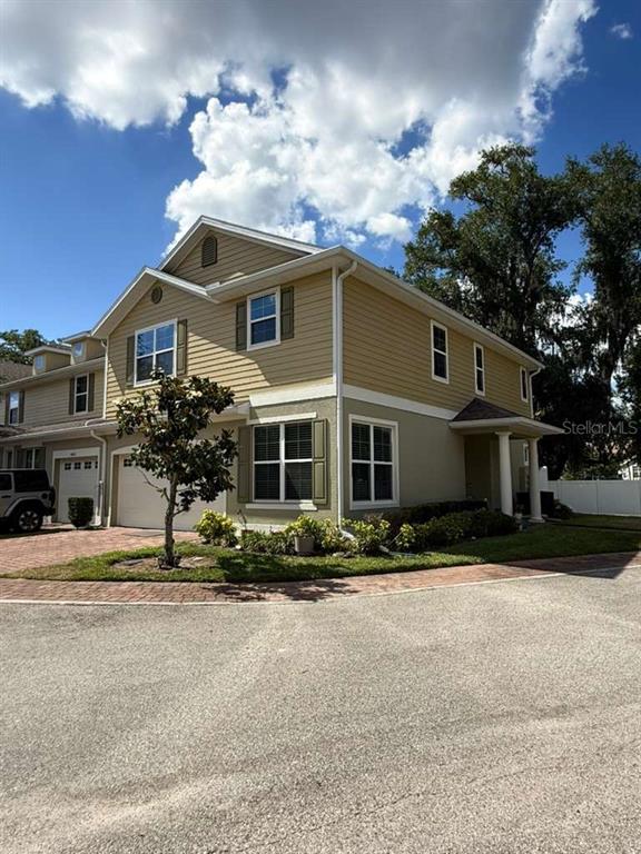 A two-story tan townhouse with a brick driveway and a small tree in front — 4800 POOLSIDE DRIVE, ST CLOUD, FL
