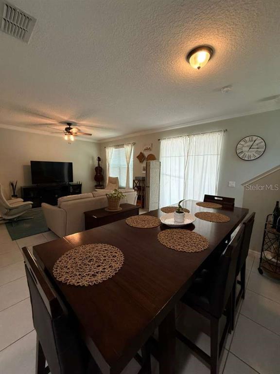 A dining area with a dark wood table sits in front of an open living room — 4800 POOLSIDE DRIVE, ST CLOUD, FL