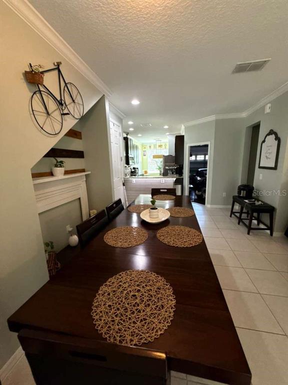 A dining room features a long wooden table with woven placemats and a bicycle wall decoration — 4800 POOLSIDE DRIVE, ST CLOUD, FL