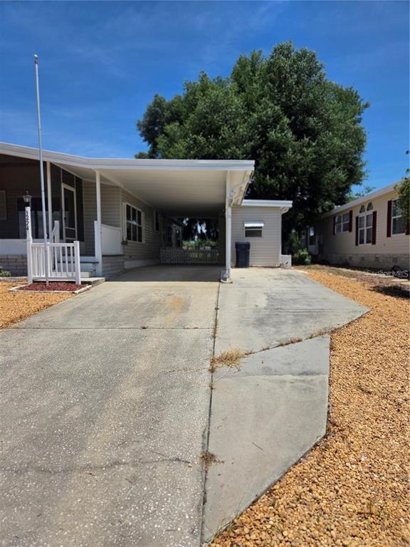 A concrete driveway leads to a covered carport attached to a single-story manufactured home — 3224 MANATEE ROAD, TAVARES, FL