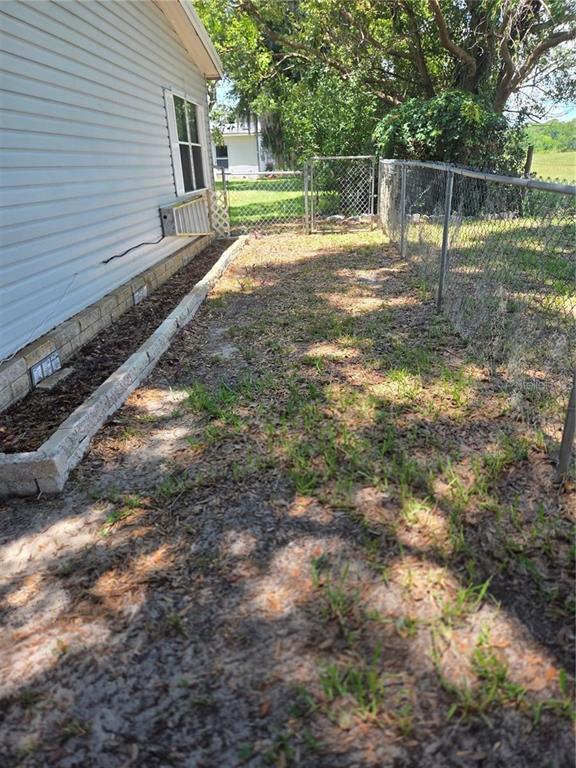 A side yard with a concrete block planter, light-colored siding, and a chain-link fence — 3224 MANATEE ROAD, TAVARES, FL
