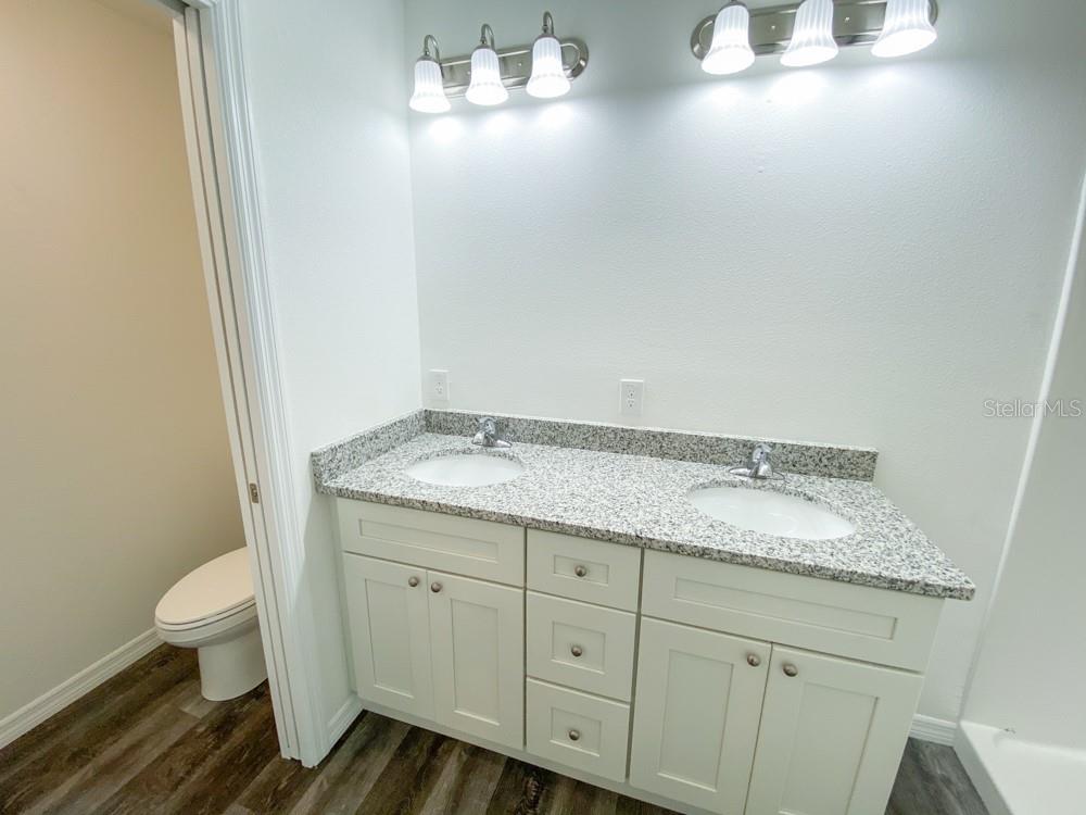 A bathroom features a double-sink vanity with a granite countertop and white cabinets — 30 JUNIPER PASS LANE, OCALA, FL