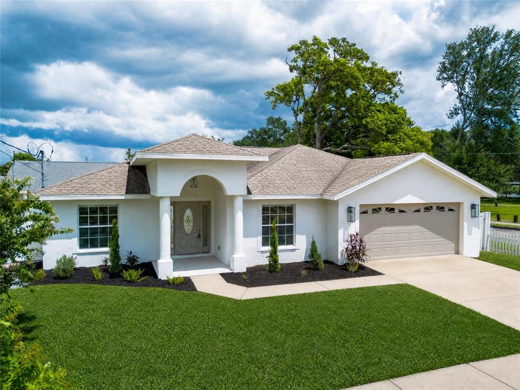 A single-story white house with a tan roof, arched entryway, and attached two-car garage — 2001 N LINCOLN AVENUE, TAMPA, FL