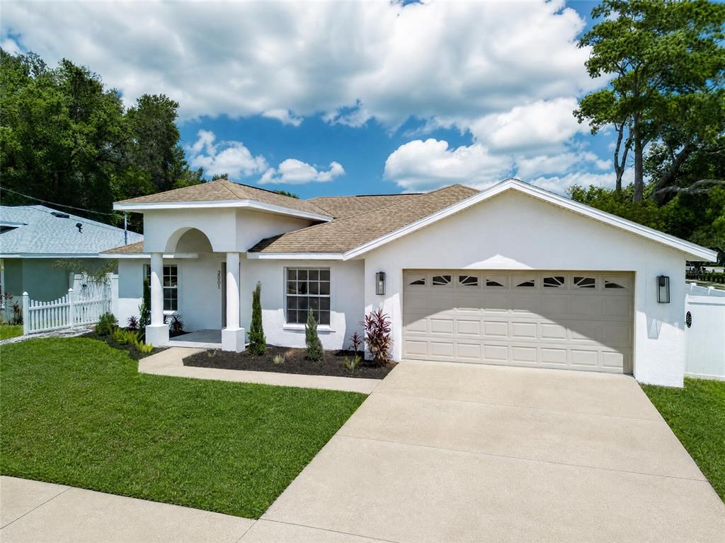 A white single-story house with a tan shingled roof, two-car garage, and a front porch — 2001 N LINCOLN AVENUE, TAMPA, FL