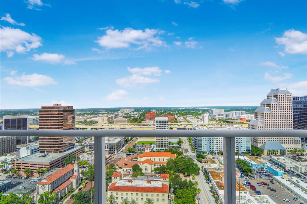 A high-rise balcony overlooks a city skyline with buildings, streets, and a blue sky — 150 E ROBINSON STREET UNIT 2608, ORLANDO, FL