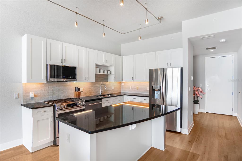 A modern kitchen features white cabinetry, black countertops, stainless steel appliances, and a central island — 150 E ROBINSON STREET UNIT 2608, ORLANDO, FL