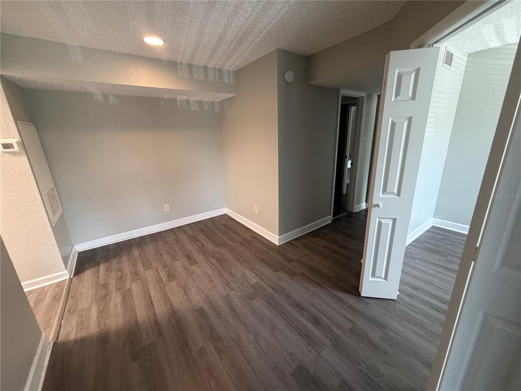 An empty room features wood-look flooring, light gray walls, and a white bi-fold closet door — 3716 IDLEBROOK CIRCLE UNIT 206, CASSELBERRY, FL