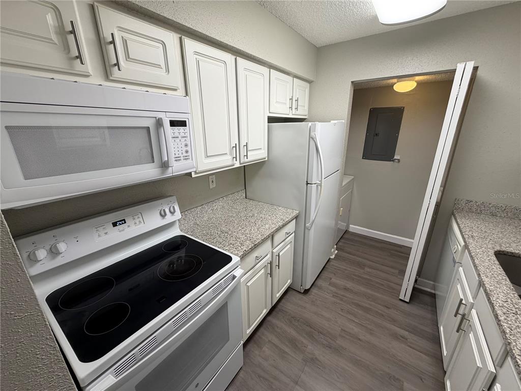 A kitchen features white cabinets, granite-look countertops, a black electric stove, and a white refrigerator — 3716 IDLEBROOK CIRCLE UNIT 206, CASSELBERRY, FL