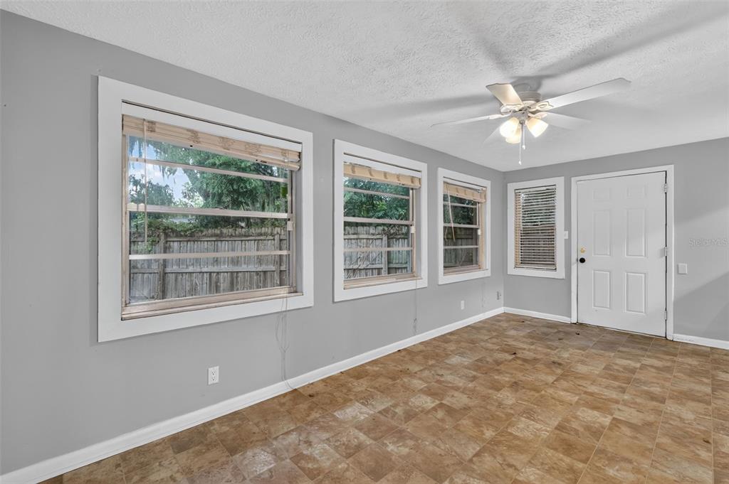 An empty room with gray walls, tile flooring, a ceiling fan, and several windows — 1305 ORANGE AVENUE, TAVARES, FL