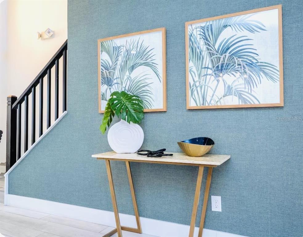 A console table with decor sits against a blue textured wall near a staircase — 1078 ORANGE COSMOS BOULEVARD, DAVENPORT, FL