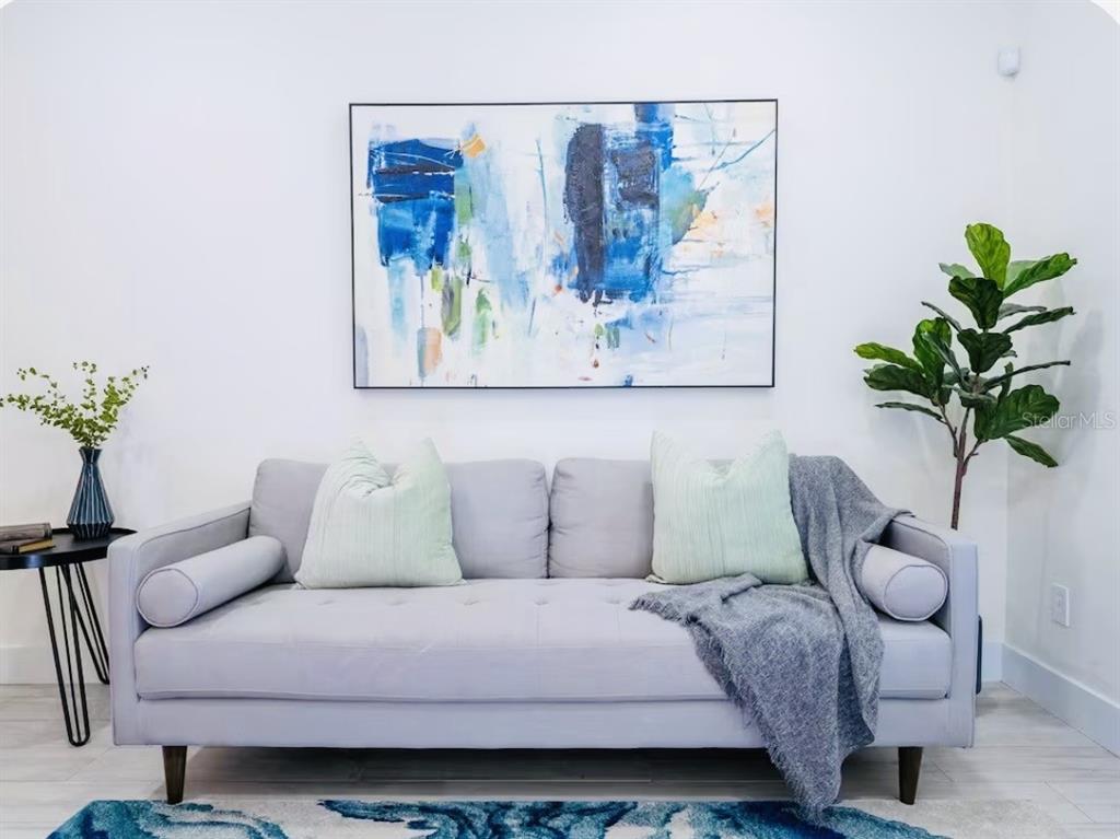 A gray sofa sits against a white wall beneath a large abstract blue painting — 1078 ORANGE COSMOS BOULEVARD, DAVENPORT, FL