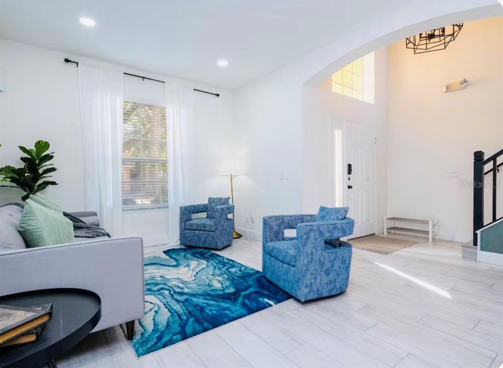 A bright living room features white tile floors, blue accent chairs, and a blue area rug — 1078 ORANGE COSMOS BOULEVARD, DAVENPORT, FL
