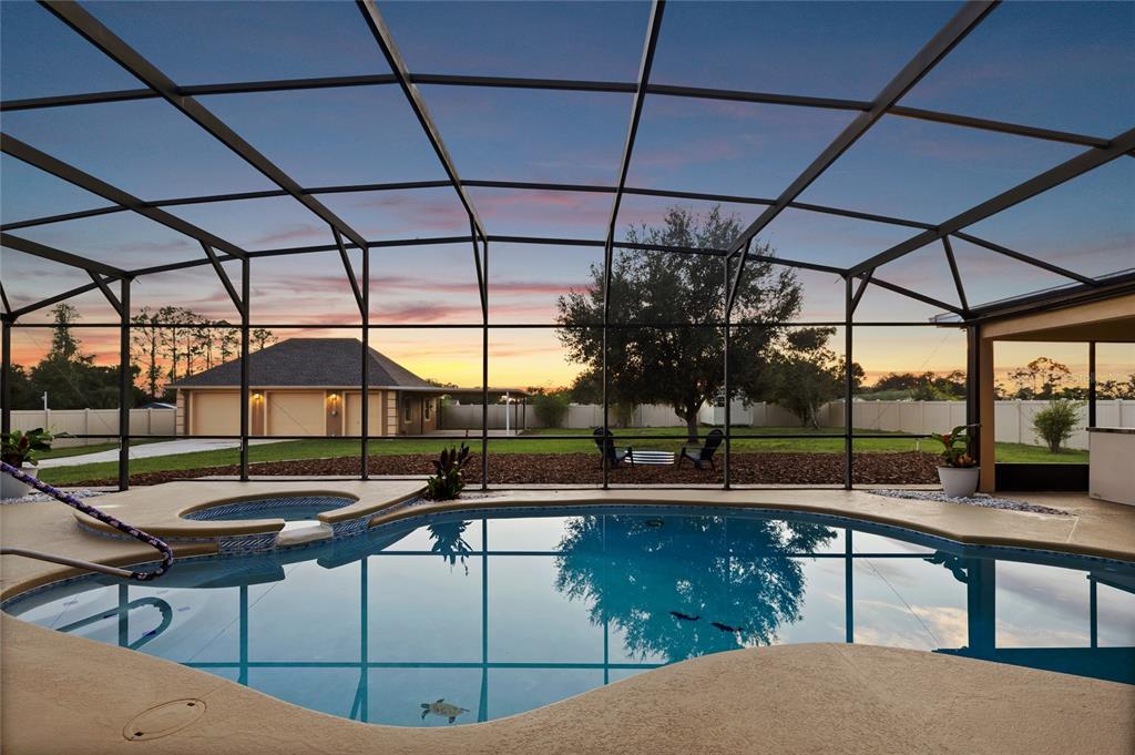 A swimming pool and hot tub are enclosed within a screened lanai overlooking a backyard — 12901 PHILLIPS ROAD, GROVELAND, FL