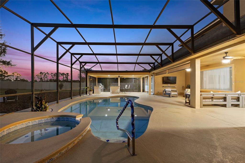 A screened-in patio features a swimming pool, a hot tub, and an outdoor kitchen area — 12901 PHILLIPS ROAD, GROVELAND, FL