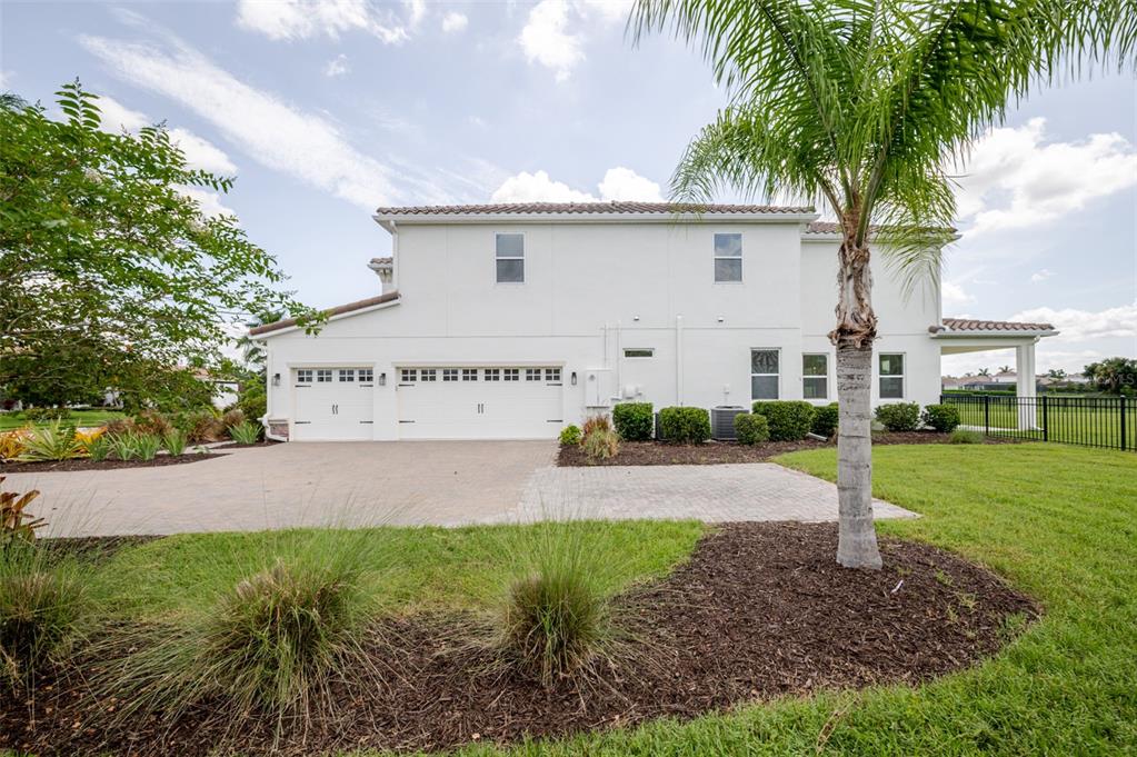 The exterior of a two-story white house features a three-car garage and a palm tree — 4789 VASCA DRIVE, SARASOTA, FL