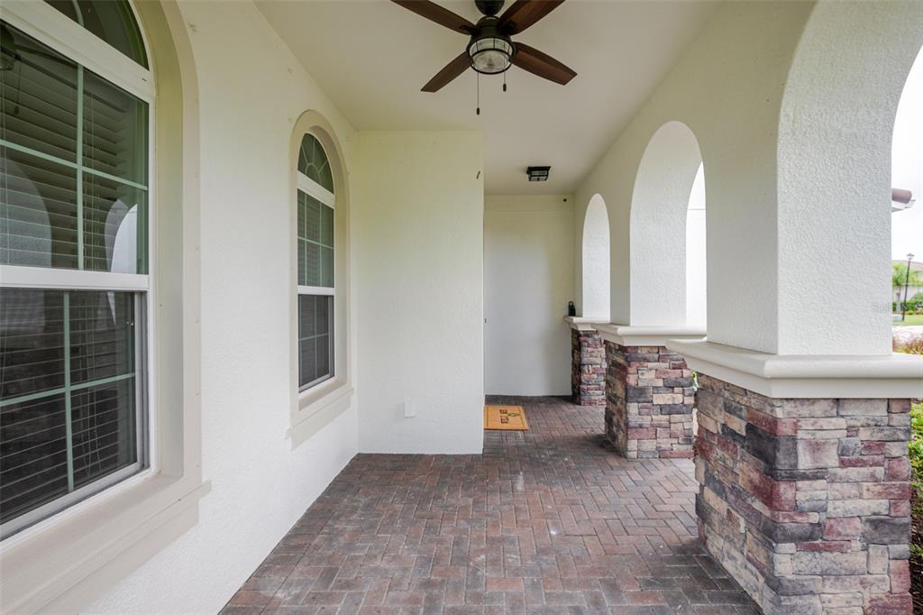 A covered front porch features brick pavers, arched columns with stone bases, and a ceiling fan — 4789 VASCA DRIVE, SARASOTA, FL