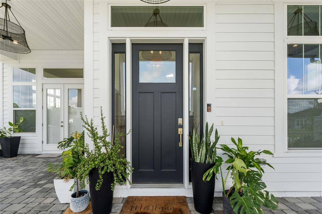 A dark gray front door with a glass panel is flanked by potted plants — 2509 SW 120TH DRIVE, GAINESVILLE, FL