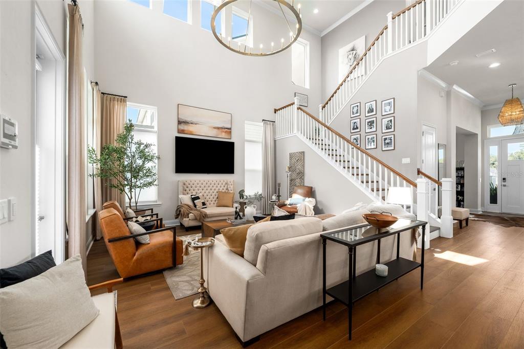 A bright, high-ceilinged living room features a staircase, hardwood floors, and neutral-toned furniture — 2509 SW 120TH DRIVE, GAINESVILLE, FL