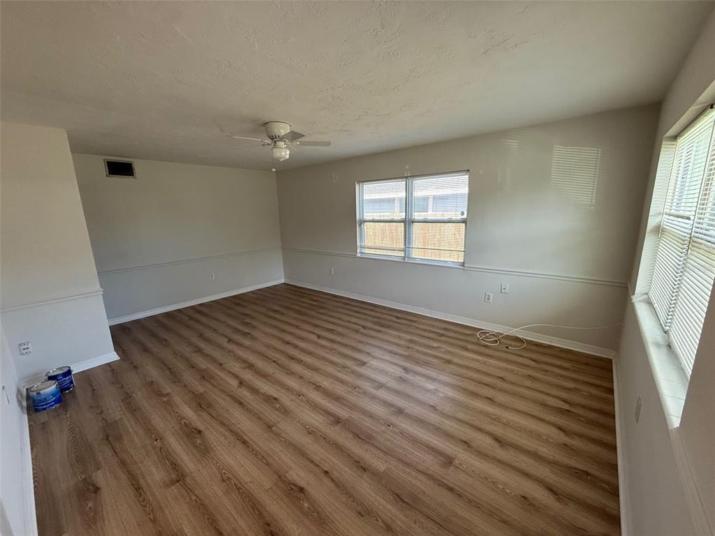 An empty room with light wood-look flooring, white walls, a ceiling fan, and two windows — 2217 20TH AVENUE W, BRADENTON, FL